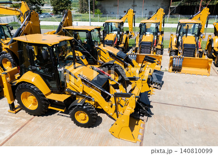 New hydraulic excavators and tractors parked at a construction machinery dealership. New hydraulic excavators and tractors parked at a construction machinery dealership. 140810099