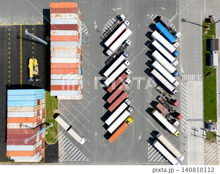 Aerial view of a logistics hub with multicolored shipping containers and trucks 140810112