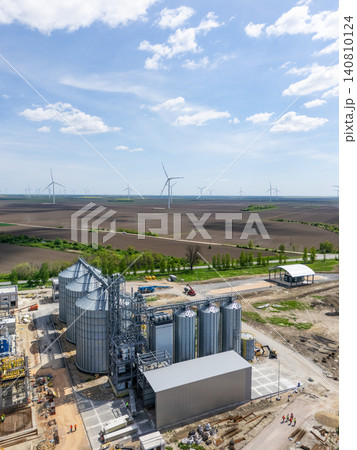 Construction of a modern agricultural grain terminal with wind turbines on the horizon. Construction of a modern agricultural grain terminal with wind turbines on the horizon. 140810124