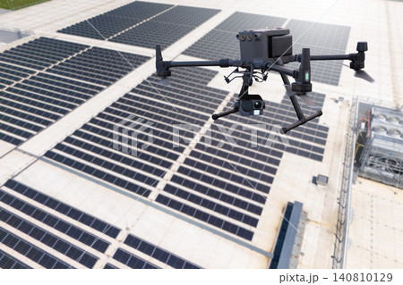 Industrial drone inspecting solar panel array on a building rooftop 140810129