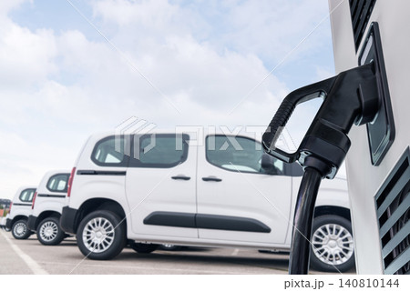 Electric vehicles charging station on a background of a row of vans. Green transportation concept. 140810144