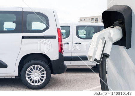 Electric vehicles charging station on a background of a row of vans. Green transportation concept. 140810148
