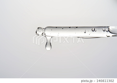 Clear serum droplet dripping from cosmetic pipette 140811302