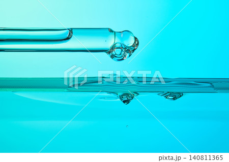Dropper dispensing blue liquid into water surface Dropper dispensing blue liquid into water surface 140811365