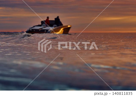 Incredible reflection on the glossy side of a modern motorboat at sunset, the Gulf of Finland, magic reflections on water surface Incredible reflection on the glossy side of a modern motorboat at sunset, the Gulf of Finland, magic reflections on water surface 140811835