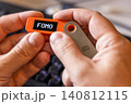 hardware Bitcoin wallet in a hands with message FOMO on screen 140812115