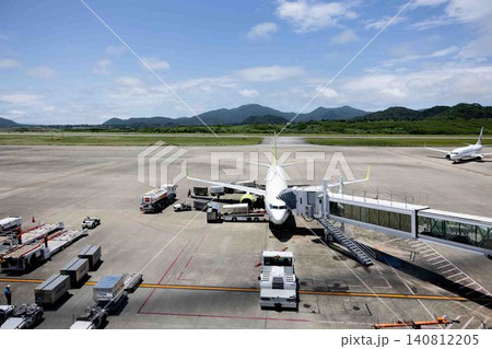 昼の空港駐機場で出発を待つ旅客機とグランドハンドリングの様子 140812205