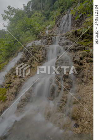 Beautiful silk effect waterfall flowing down mossy rock cliffs at Goa Tetes Lumajang Indonesia Beautiful silk effect waterfall flowing down mossy rock cliffs at Goa Tetes Lumajang Indonesia 140812384