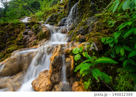 Beautiful silk effect waterfall flowing down mossy rock cliffs at Goa Tetes Lumajang Indonesia 140812389