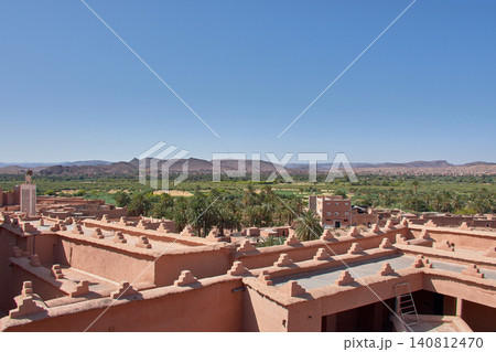 The stepped battlements of the Kasbah Taourirt stand out against the backdrop of the vast green oasis in Ouarzazate, Morocco. The stepped battlements of the Kasbah Taourirt stand out against the backdrop of the vast green oasis in Ouarzazate, Morocco. 140812470