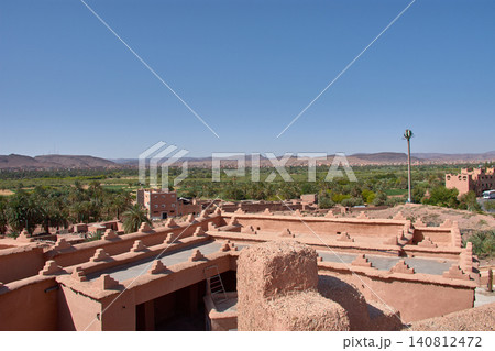 The stepped battlements of the Kasbah Taourirt stand out against the backdrop of the vast green oasis in Ouarzazate, Morocco. The stepped battlements of the Kasbah Taourirt stand out against the backdrop of the vast green oasis in Ouarzazate, Morocco. 140812472