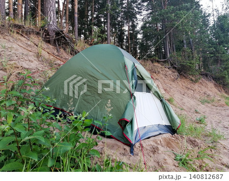 tourist tent of green color on sandy slope near roots of trees tourist tent of green color on sandy slope near roots of trees 140812687