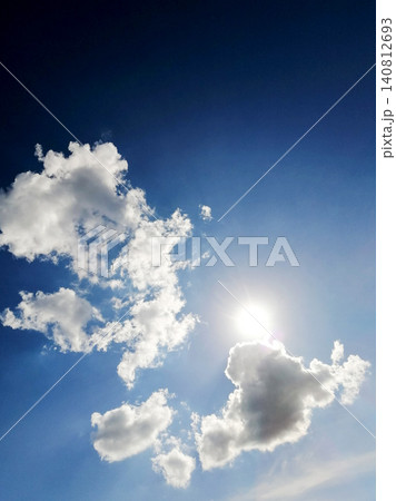 bright sun shines in blue sky through white fluffy clouds 140812693
