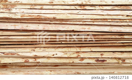 many thin wooden slats with bark arranged horizontally in rows 140812718
