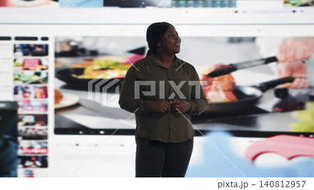 Woman browses interconnected video feeds on a large digital display wall. 140812957