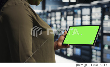 Programmer uses green screen tablet in a server farm to plan disaster recovery and strengthen data protection. Programmer uses green screen tablet in a server farm to plan disaster recovery and strengthen data protection. 140813013