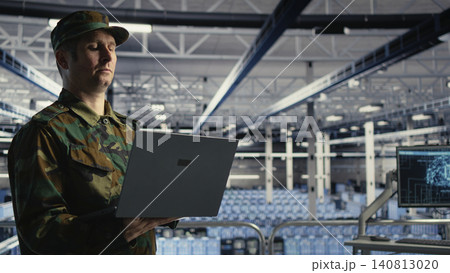 Army soldier operates a laptop in a military data center to deploy AI technology for defense infrastructure. Army soldier operates a laptop in a military data center to deploy AI technology for defense infrastructure. 140813020