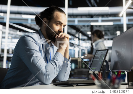Data center worker monitors system performance and troubleshoots software issues affecting server operations. Data center worker monitors system performance and troubleshoots software issues affecting server operations. 140813074