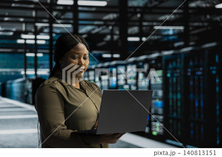 System operator uses a laptop computer in a data center to monitor equipment, manage workflows, and support reliable infrastructure. 140813151