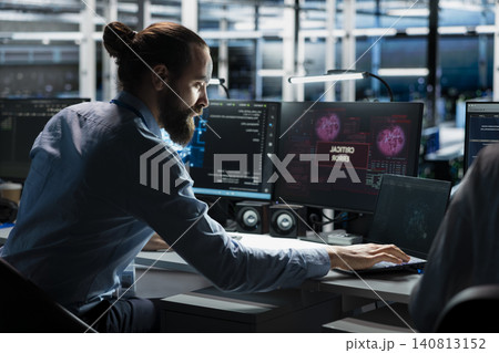 Technician works with a computer workstation in a server hub to support artificial intelligence systems. Technician works with a computer workstation in a server hub to support artificial intelligence systems. 140813152