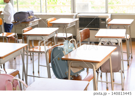 多様な色のカラフルなランドセルが机や椅子に置かれた日の光が差し込む明るい小学校の教室 多様な色のカラフルなランドセルが机や椅子に置かれた日の光が差し込む明るい小学校の教室 140813445