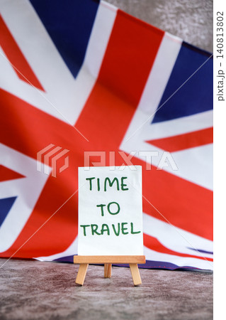 Paper note with words TIME TO TRAVEL on National symbol of Great Britain. British wave the UK silky flag background. Travel destination tourism  140813802