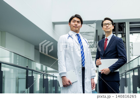 病院でミーティングする白衣の医師とビジネスマン 病院でミーティングする白衣の医師とビジネスマン 140816265
