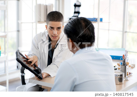 Woman doctor discussing illness symptom of man patient at clinic looking tablet. 140817545