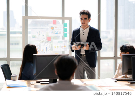 Businessman giving presentation on glass board, manager speaking to diverse team during meeting. 140817546