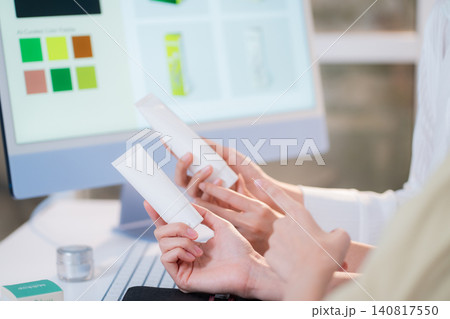 Two asian woman discussing cosmetic tube packaging sitting at modern home office. Two asian woman discussing cosmetic tube packaging sitting at modern home office. 140817550