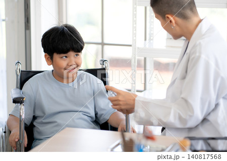 Caucasian woman doctor talking with young asian boy patient sitting in wheelchair for examining. 140817568