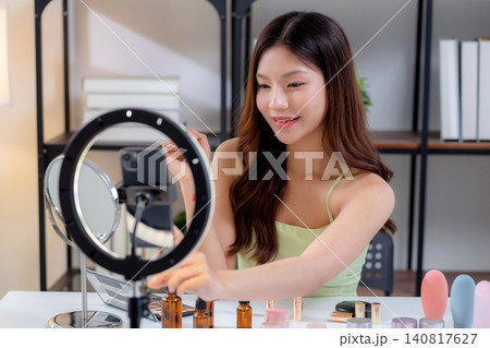 Young asian beauty influencer testing multiple lipstick shades on arm while recording makeup review. 140817627