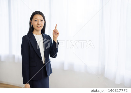窓辺で人差し指を一本立てる若い日本人のビジネスウーマン 窓辺で人差し指を一本立てる若い日本人のビジネスウーマン 140817772