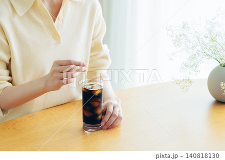 家でアイスコーヒーを飲む若い女性の手元 140818130