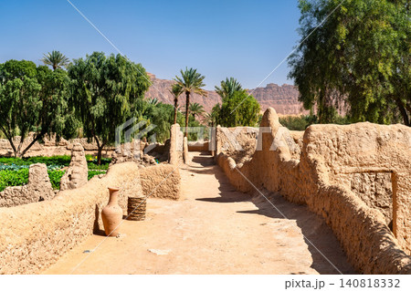 Detailed view of traditional mud brick walls and lush palm trees in the Daimumah Oasis of AlUla, Saudi Arabia. Detailed view of traditional mud brick walls and lush palm trees in the Daimumah Oasis of AlUla, Saudi Arabia. 140818332