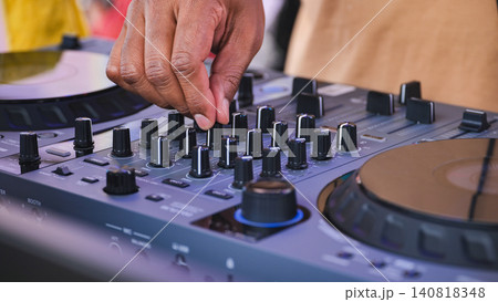 DJ hand adjusting controls on mixer for live music performance at an event DJ hand adjusting controls on mixer for live music performance at an event 140818348