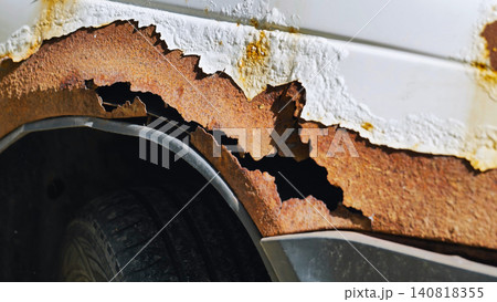 Corroding car body showing severe rust and peeling white paint on a wheel arch in Moscow Corroding car body showing severe rust and peeling white paint on a wheel arch in Moscow 140818355