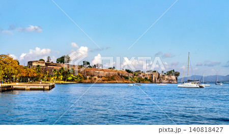Scenic view of the historic Fort Saint Louis fortification on the coast of Fort de France, Martinique, seen from the bay with sailboats on the blue water. Scenic view of the historic Fort Saint Louis fortification on the coast of Fort de France, Martinique, seen from the bay with sailboats on the blue water. 140818427