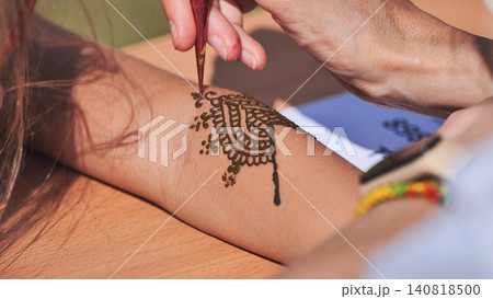 Artist drawing henna tattoo on woman arm in India Artist drawing henna tattoo on woman arm in India 140818500