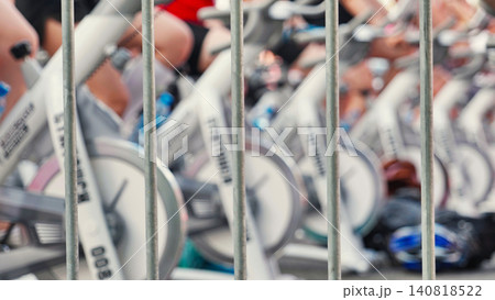 Athletes pedaling on exercise bikes during sports day behind a fence Athletes pedaling on exercise bikes during sports day behind a fence 140818522