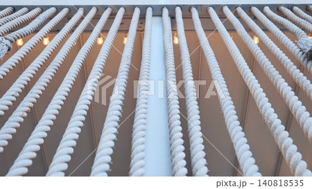 White nautical ropes hanging creating a repeating pattern with warm lights White nautical ropes hanging creating a repeating pattern with warm lights 140818535