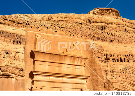 View of the intricate rock-cut tomb facade and sandstone cliffs at the Hegra archaeological site in Al Ula, Saudi Arabia. View of the intricate rock-cut tomb facade and sandstone cliffs at the Hegra archaeological site in Al Ula, Saudi Arabia. 140818753