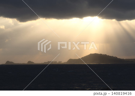 雲の隙間から神々しい天使の梯子が海と島へ降り注ぐドラマチックな風景 140819416