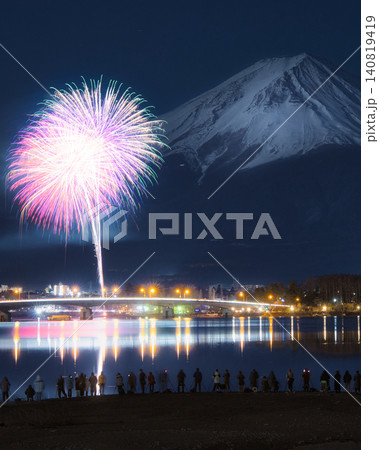 冬の河口湖大橋に打ち上がる鮮やかな花火と冠雪した美しい富士山 140819419
