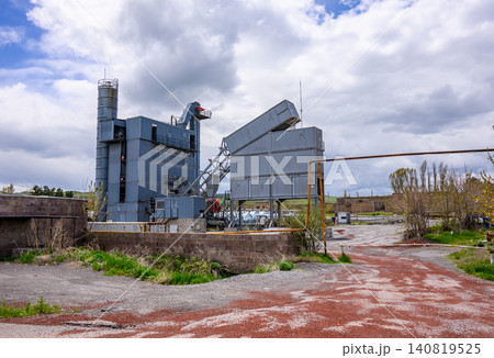 Desolate industrial site with rusted equipment and overgrown vegetation Desolate industrial site with rusted equipment and overgrown vegetation 140819525