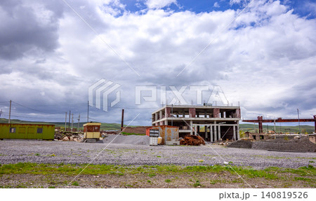 Ruined building site with broken walls and scattered debris under overcast skies 140819526