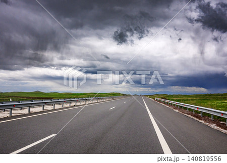 Storm clouds loom over empty asphalt road Storm clouds loom over empty asphalt road 140819556
