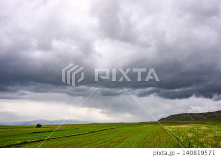 Storm clouds gather above green fields with distant hills Storm clouds gather above green fields with distant hills 140819571
