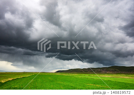Stormy sky casts shadow over rolling green fields with no visible life forms Stormy sky casts shadow over rolling green fields with no visible life forms 140819572