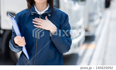 トラックを背景に胸に手を当てて立つ女性 トラックを背景に胸に手を当てて立つ女性 140820092